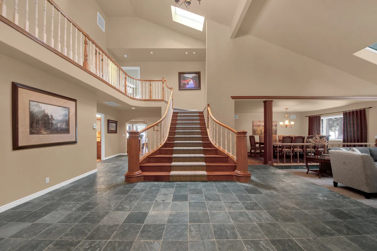 A view of the grand staircase adjacent to a stylish dining area, with artwork enhancing the elegant ambiance. The setting hints at both quiet moments by the stairs and lively family meals, embodying the home’s blend of privacy and sociability.