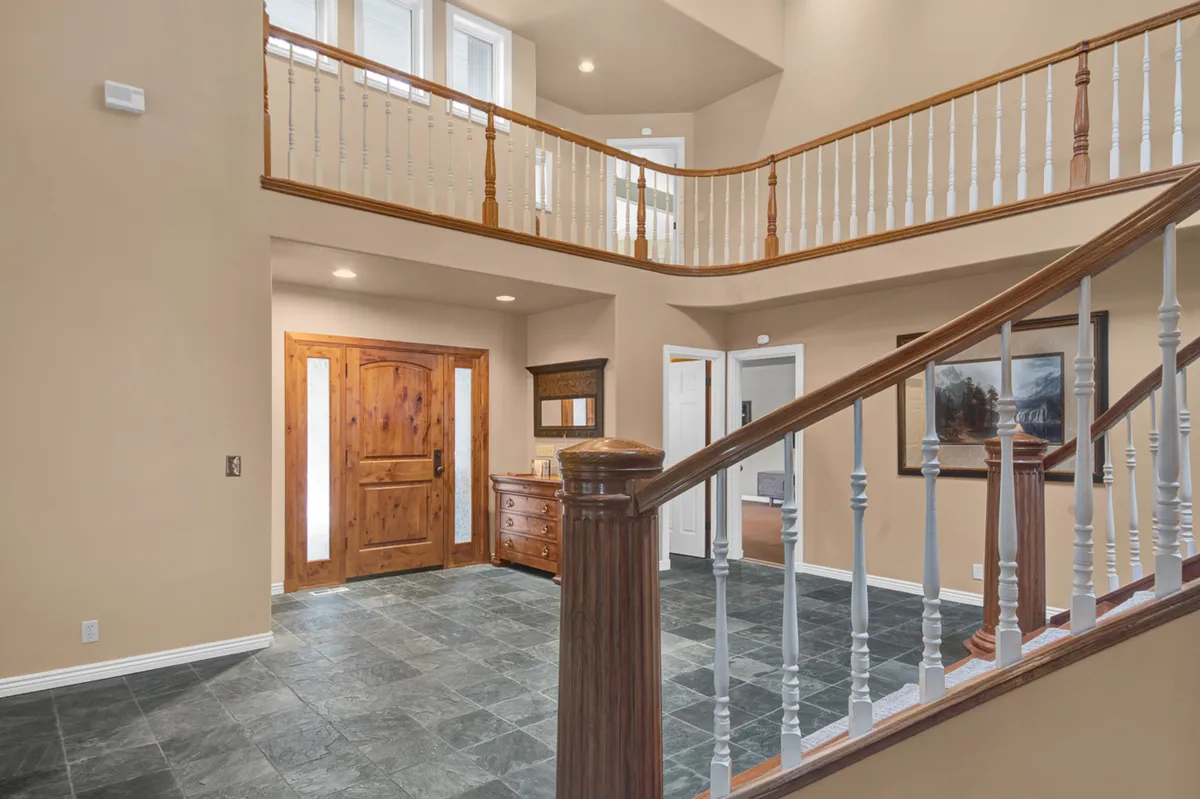 The entrance door opens onto a view of the staircase and inviting furniture, highlighting the transition from outside to the home’s heart. The scene conveys a warm welcome and the anticipation of milestones and memorable moments.