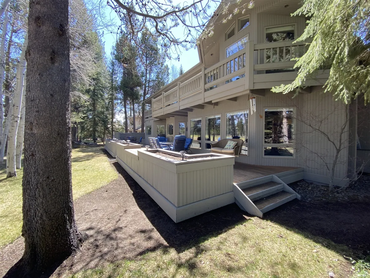 This tranquil exterior image focuses on a balcony with comfortable seating and is surrounded by mature trees, with large windows that create a sense of indoor-outdoor flow. The setting encourages relaxation and socializing while immersed in nature.